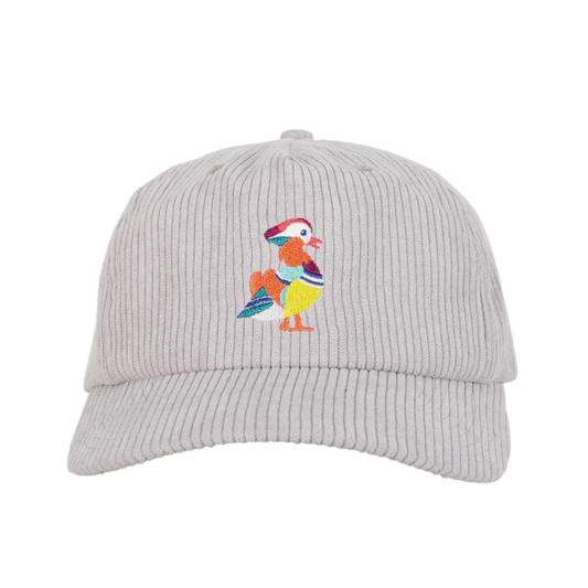 A front view of a recycled corduroy hat from Bird Club, featuring an embroidered logo of a colorful mandarin duck. The hat is part of a sustainable brand collection, emphasizing eco-friendly materials and ornithology. The intricate embroidery showcases the brand's attention to detail and passion for birding. The light gray corduroy fabric adds a textured, stylish element to the hat, appealing to environmentally conscious consumers and bird enthusiasts alike.