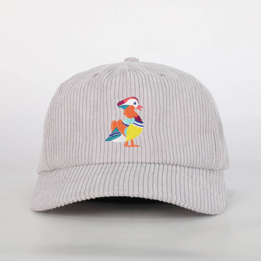 A front view of a recycled corduroy hat from Bird Club, featuring an embroidered logo of a colorful mandarin duck. The hat is part of a sustainable brand collection, emphasizing eco-friendly materials and ornithology. The intricate embroidery showcases the brand's attention to detail and passion for birding. The light gray corduroy fabric adds a textured, stylish element to the hat, appealing to environmentally conscious consumers and bird enthusiasts alike. 