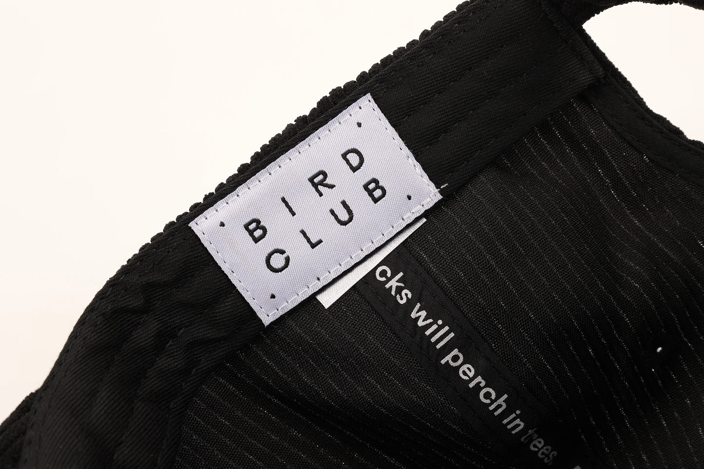 Detailed close-up of the Bird Club label stitched inside a black corduroy hat, emphasizing quality craftsmanship and sustainable design. Perfect for gifts for birders or eco-friendly gifts for bird lovers.