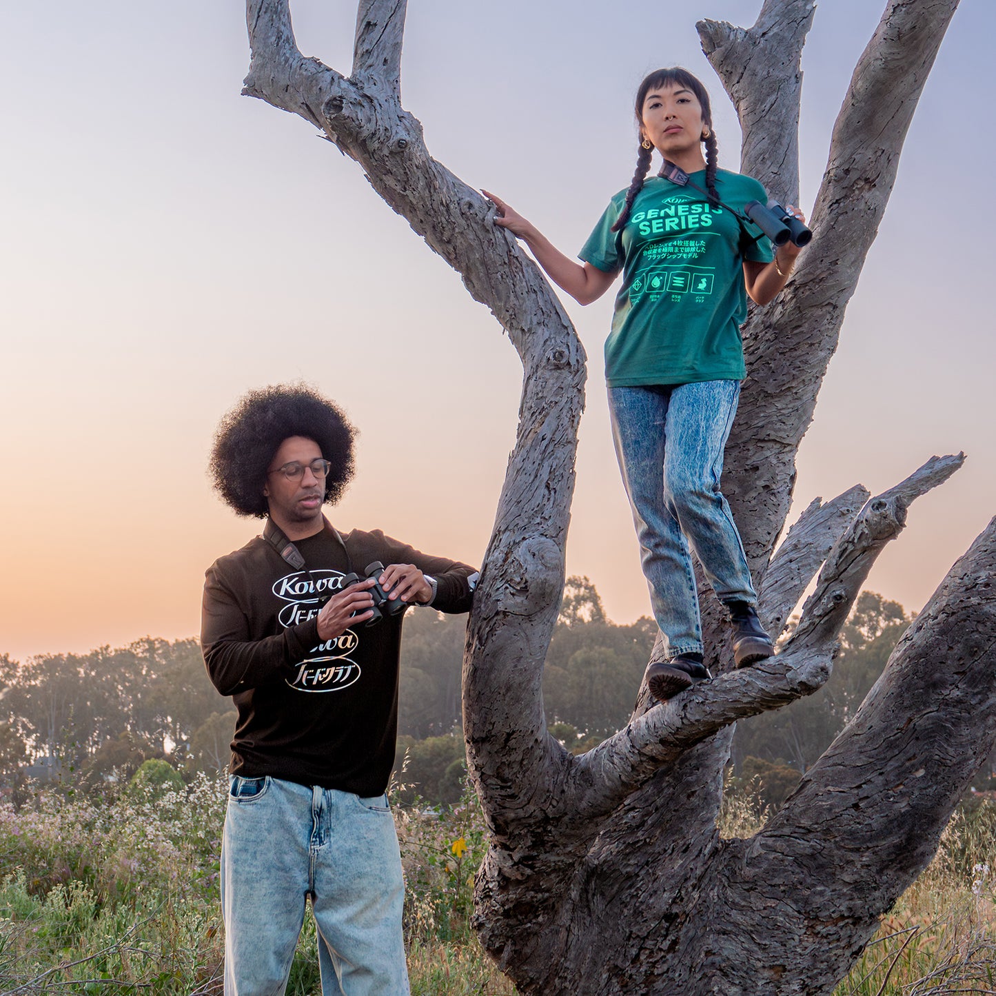 Two individuals in Bird Club apparel enjoying nature, with one standing on a tree branch and the other holding binoculars, showcasing unique bird watcher gifts and gifts for birders. Featuring ornithology shirts from a sustainable brand, perfect for bird enthusiasts passionate about eco-friendly fashion and birdwatching.