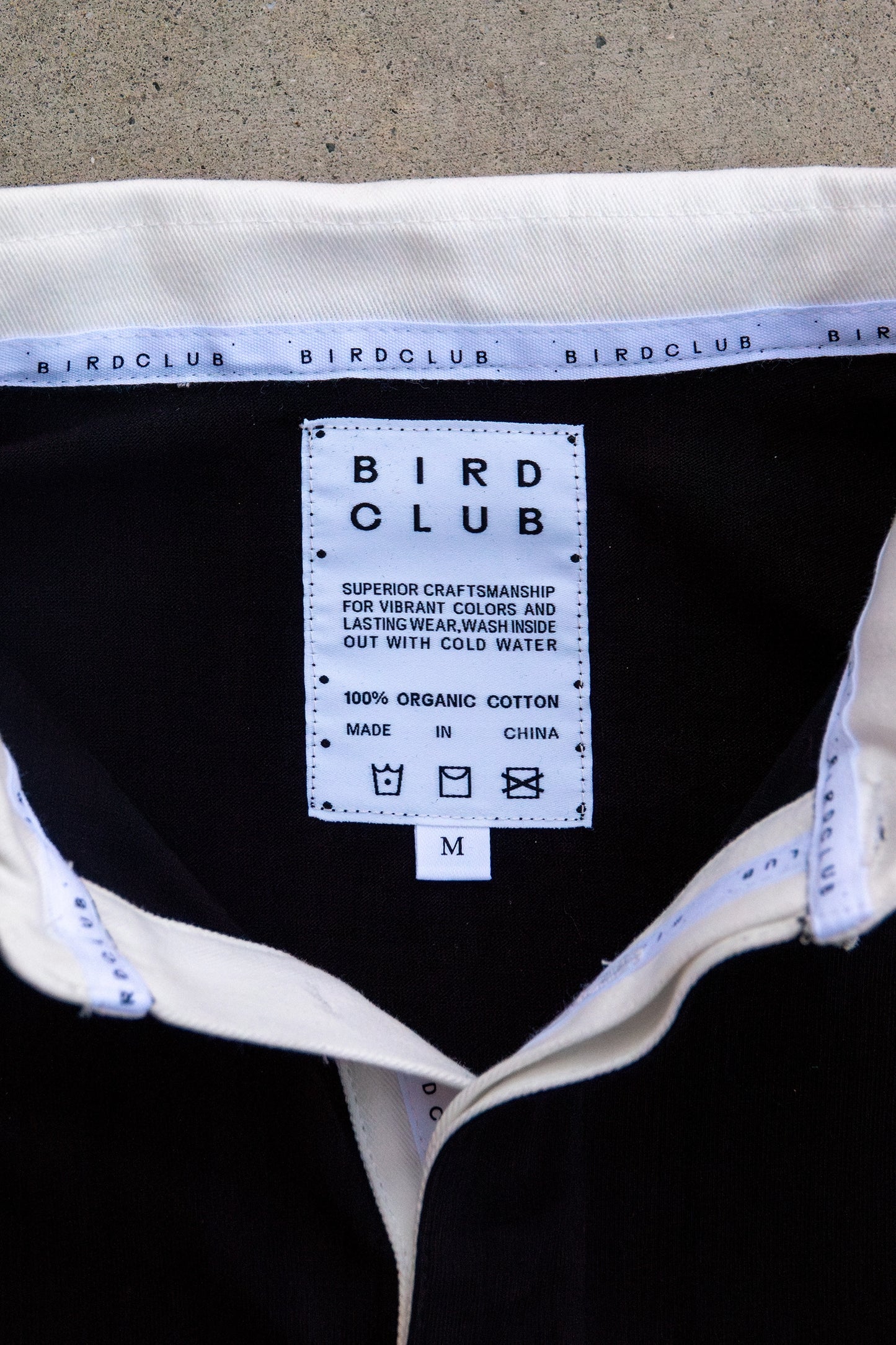 Interior label of the Bird Club ornithology shirt, displaying care instructions and organic cotton material. An excellent choice for gifts for birders and eco-friendly fashion lovers.