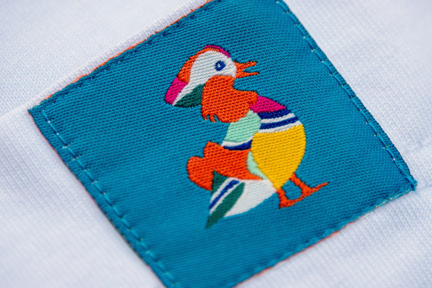 Super closeup of the Mandarin Duck pocket detail on the white eco-friendly t-shirt, designed for nature lovers. An ideal gift for bird watchers or gifts for bird lovers.