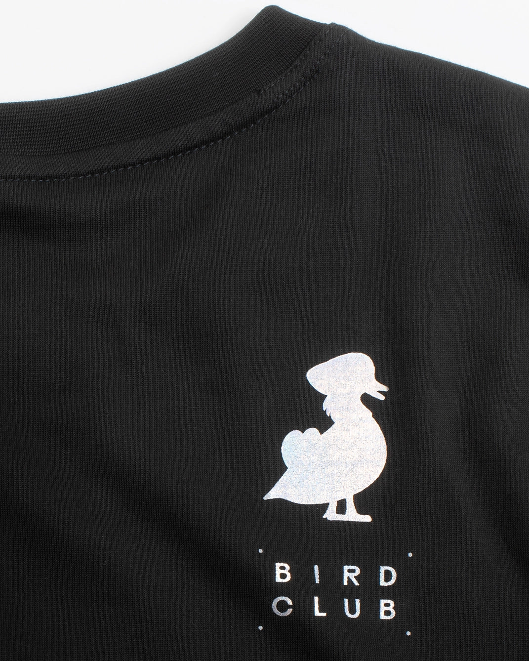 The back view of a black long-sleeve T-shirt from the Bird Club and Kowa collaboration, featuring a subtle iridescent gradient. The upper back displays a small logo with a bird illustration and the text "Bird Club" highlighting the connection to ornithology. This T-shirt is part of a sustainable brand collection, merging eco-friendly materials with a passion for bird watching.